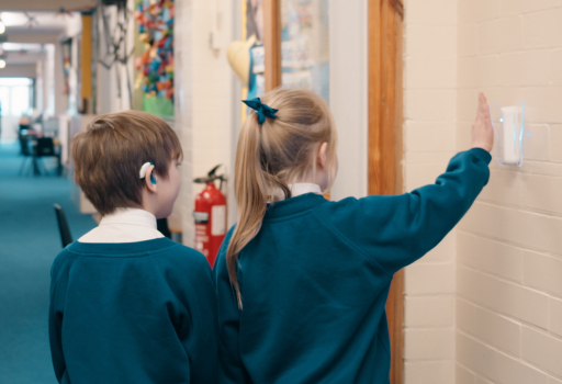 Two pupils pointing at a Butterfly in a school corridor