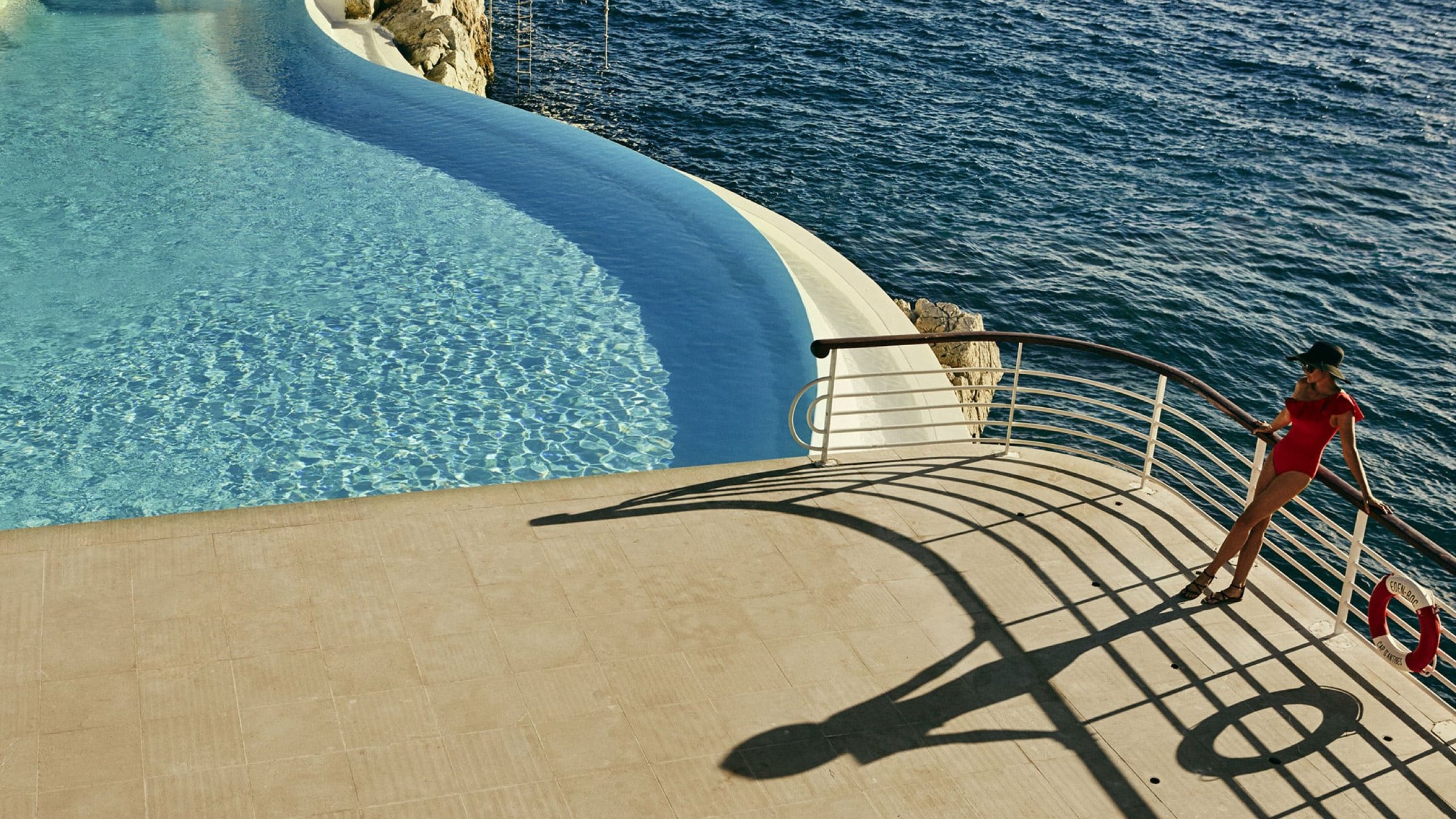 Guest in a red swimsuit on a sweeping balcony above a seawater pool